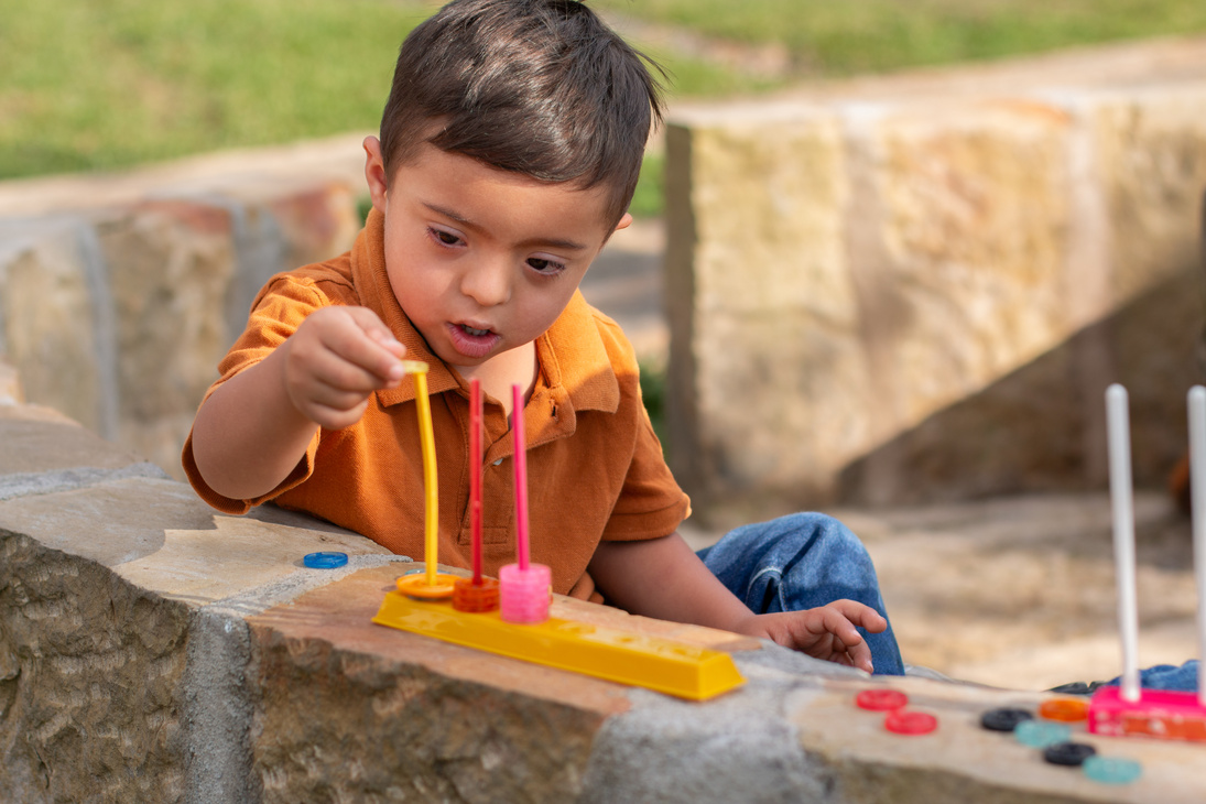 A child with intellectual disability learning with educational toys in a natural park